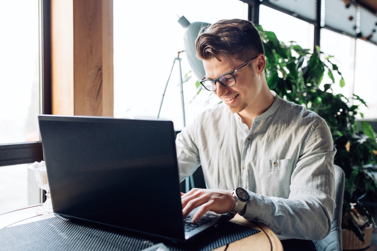 Man With Glasses Typing And Browsing Different Website Designs On Laptop