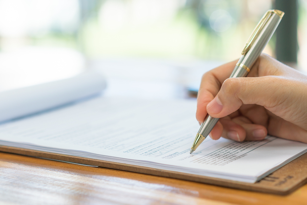 Hand And Pen Writing On A Clipboard