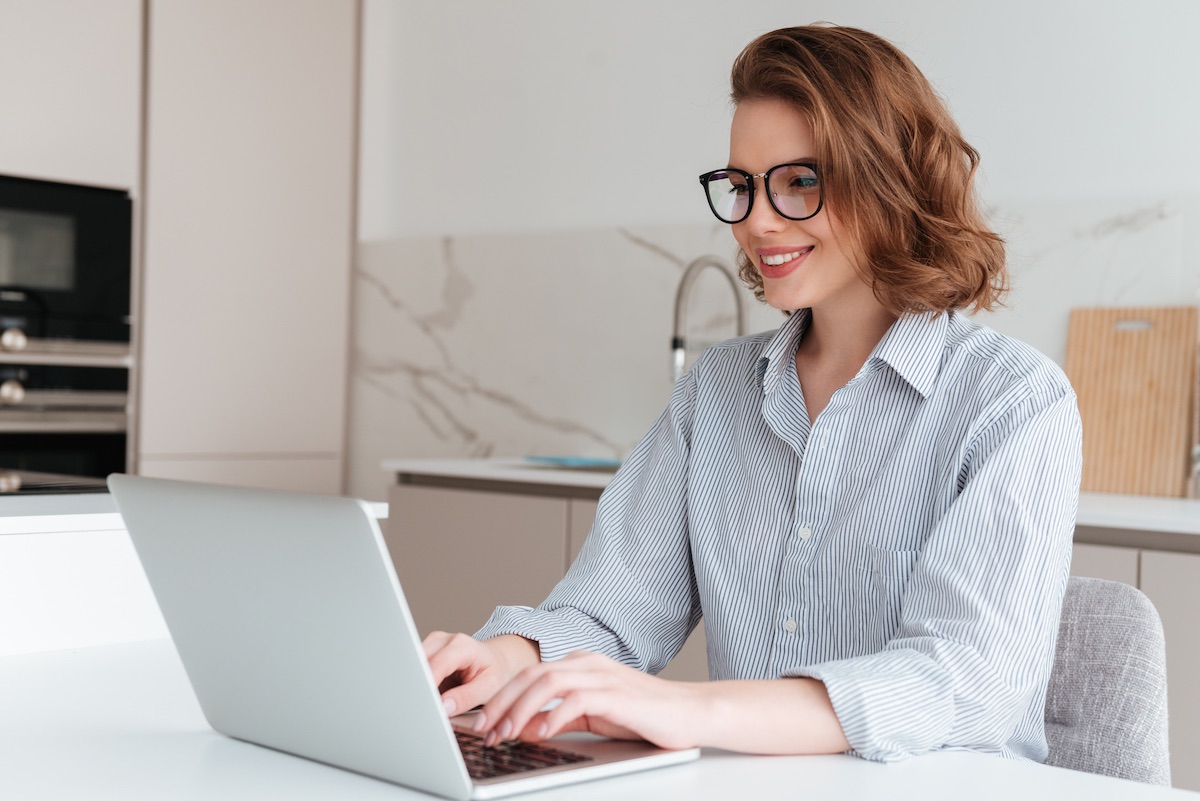 Smiling Woman With Glasses Working On Her Laptop On Custom Wordpress Website Design