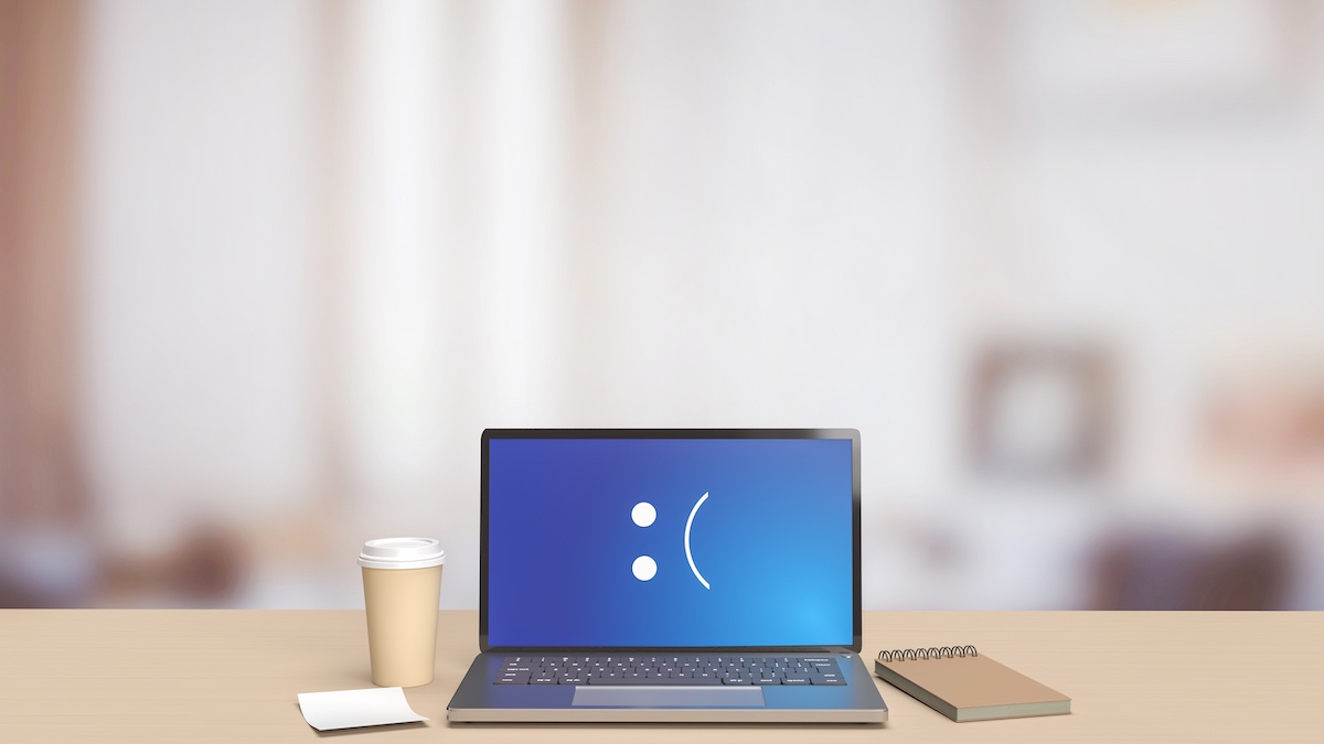 Laptop On Desk With Screen Showing Nothing But A Sad Face . A Coffee Cup Is Next To The Laptop