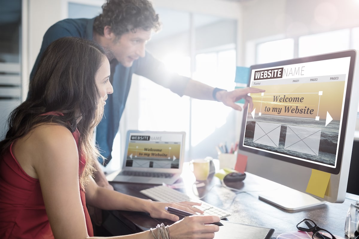 two people at the desktop computer showing at website design template