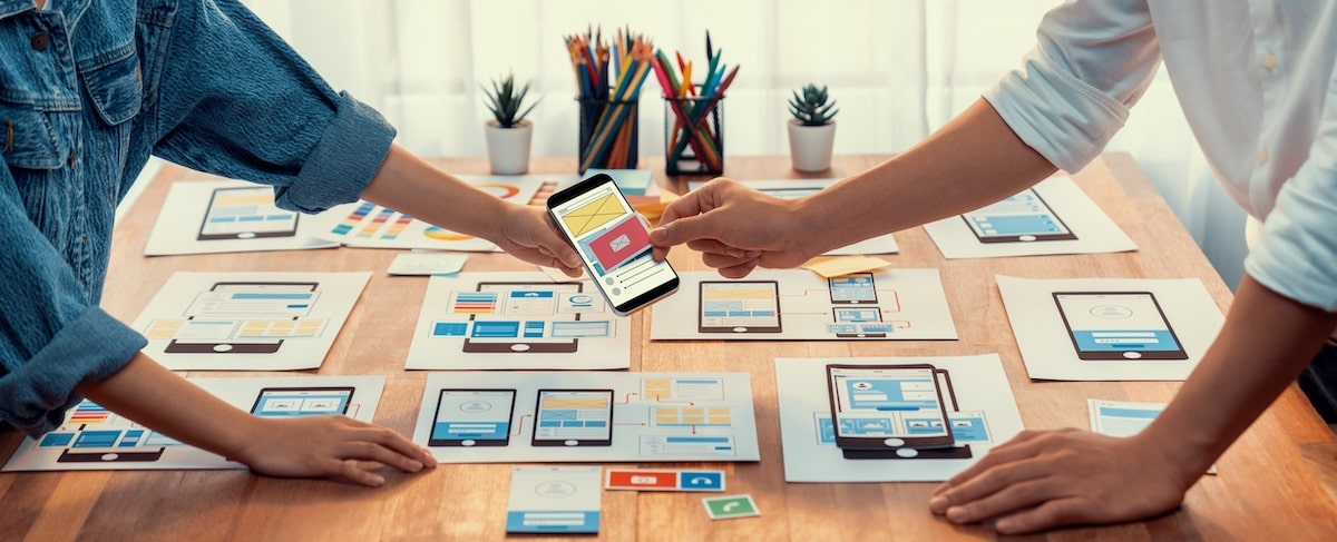 Man Holding A Mobile Over The Tables With Many Images Of Ipads That Shows Responsive Web Design