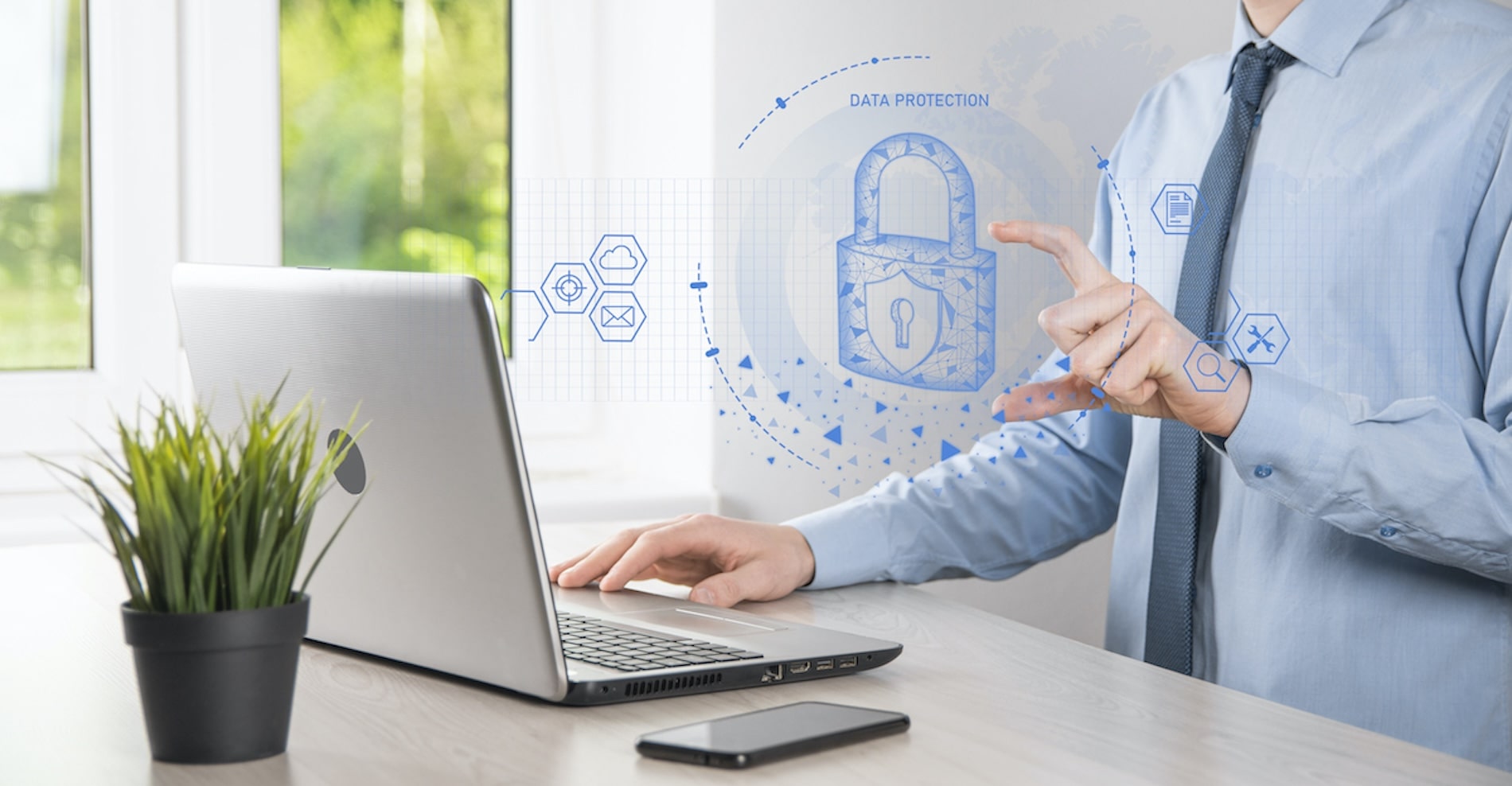 businessman at laptop pointing at a superimposed blue padlock symbol above the keyboard