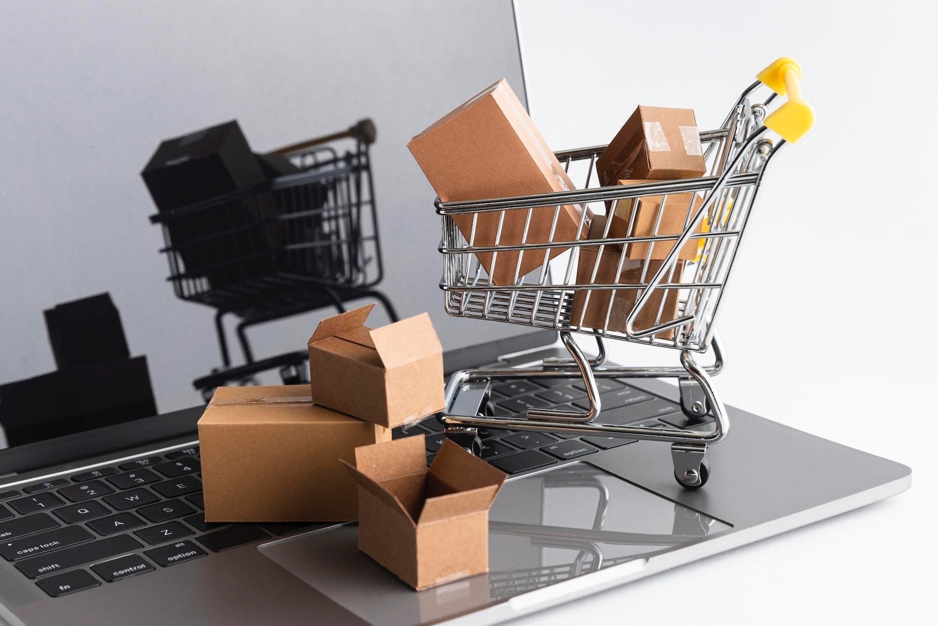 Mini shopping cart with cardboard boxes on top of laptop