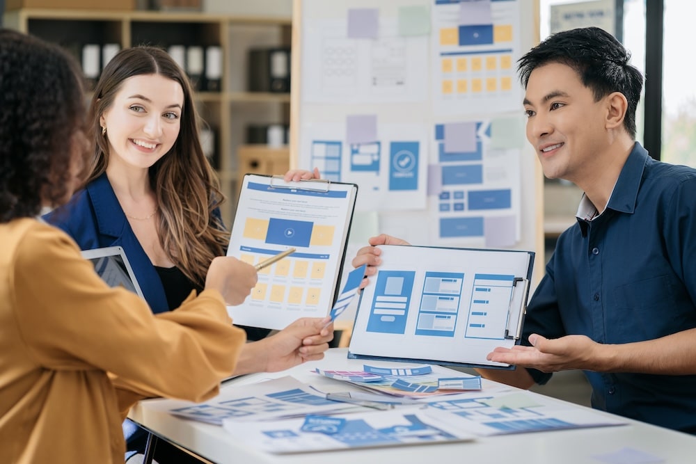 Web Designers Discussing Website Layouts, Showing Why Diy Websites Kill Client Confidence Compared To Professional Design
